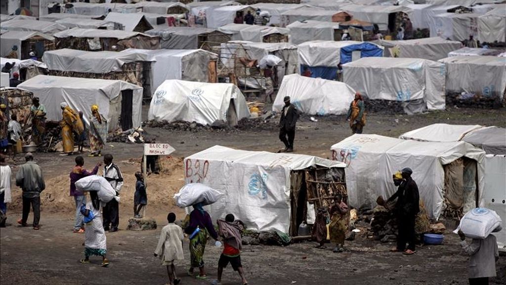 Varias personas transportan baterías de cocina, sábanas y mosqueteras que se les han sido entregadas en el campo de refugiados de Kibati, República Democrática del Congo. EFE/Archivo