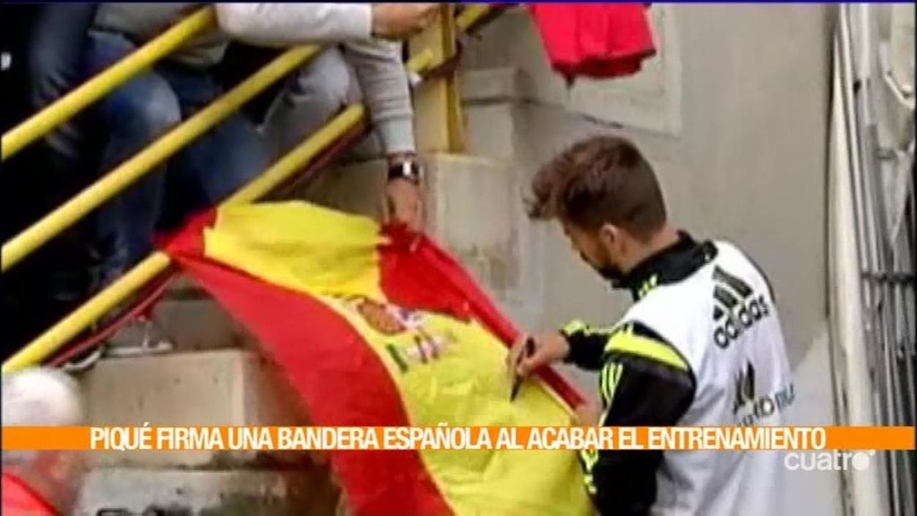 Piqué reacciona a los pitos silbando pero termina firmando una bandera de España