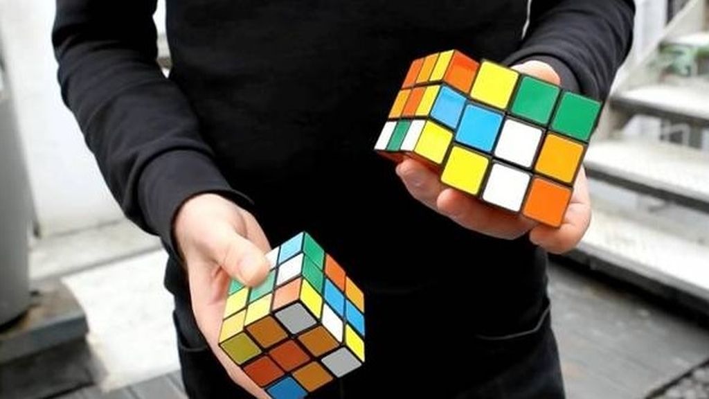 Un joven resuelve tres cubos mágicos mientras realiza malabares