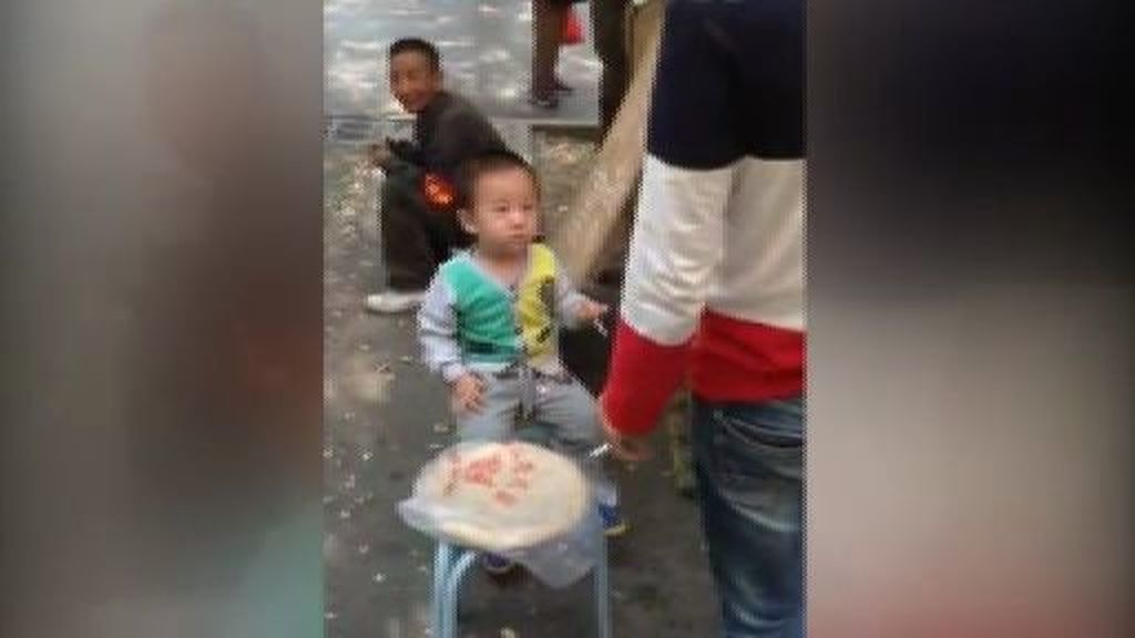 Un niño chino fuma en plena acera entre la risa de los viandantes
