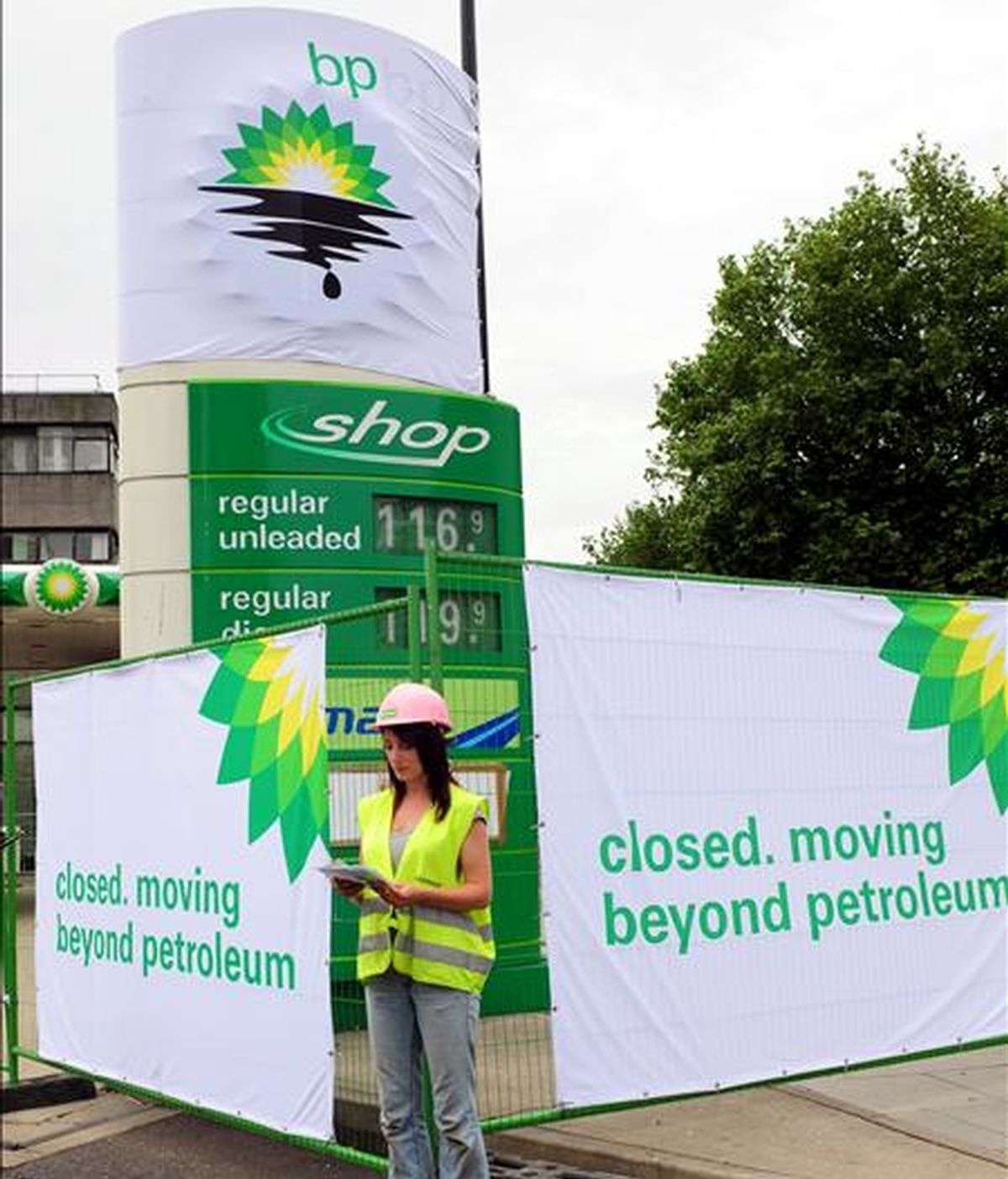 Una activista de la organización ecologista Greenpeace lee un documento junto a una pancarta de denuncia en una estación de servicio de la British Petroleum (BP) en Londres (Reino Unido), hoy, 27 de julio. EFE