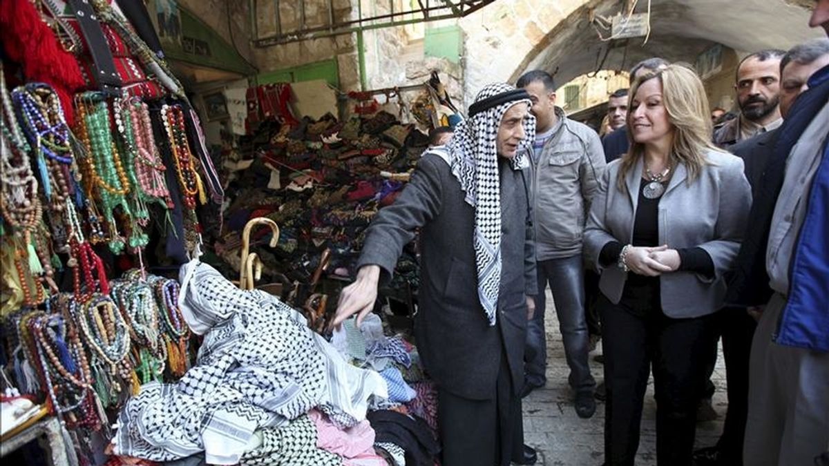 Un comerciante ofrece pañuelos palestinos a la ministra de Exteriores, Trinidad Jiménez , durante el recorrido que realizó por el casco antiguo de la ciudad de Hebrón (Cisjordania) hoy. EFE