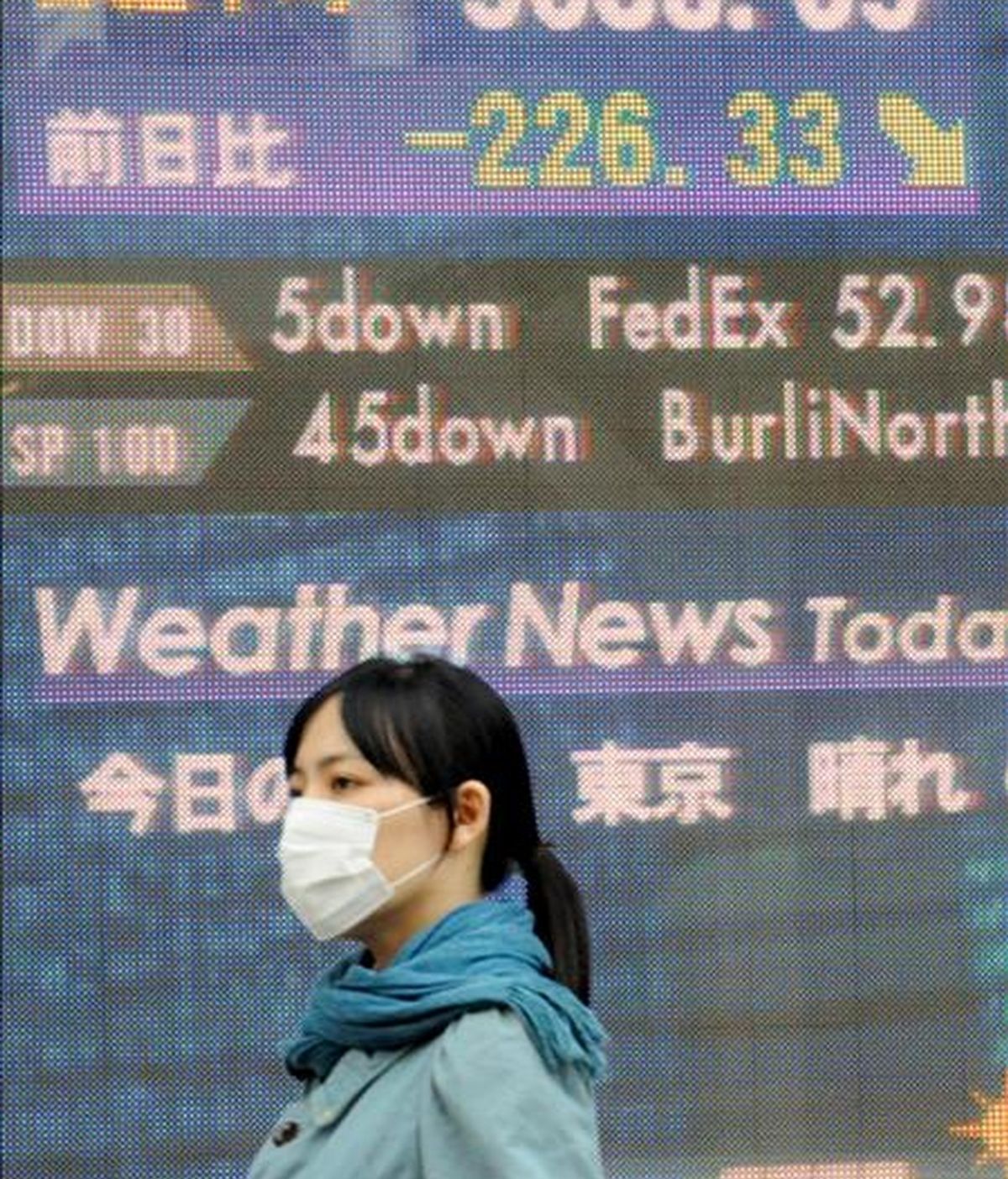 Una mujer pasa por delante de un panel electrónico en el que se muestran los valores de la Bolsa de Tokio (Japón). EFE/Archivo