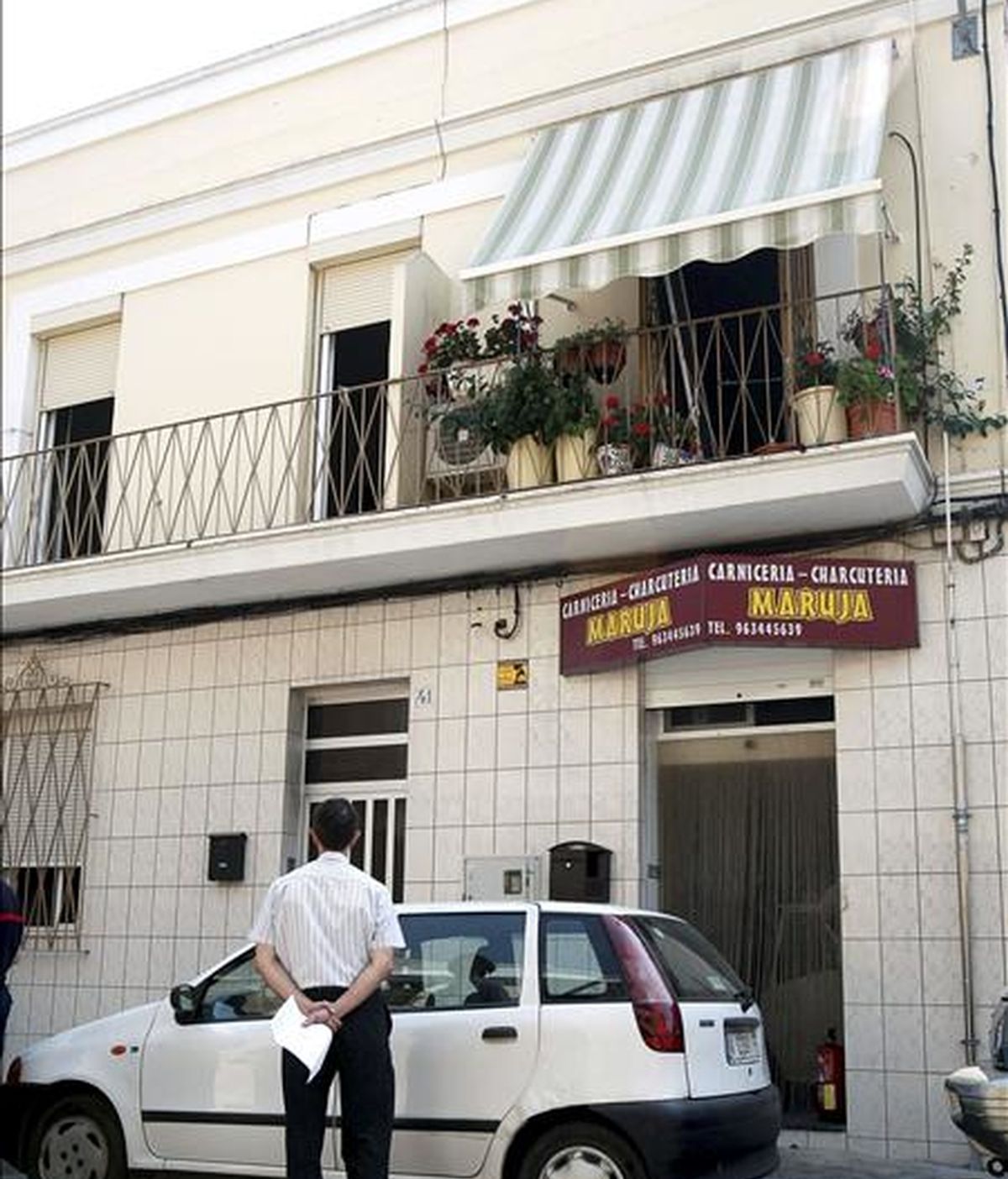 Un trabajador del retén fúnebre observa la vivienda del primer piso en el que ha fallecido una anciana ciega de 84 años en el incendio registrado en su domicilio del barrio del Oliveral de Valencia. EFE