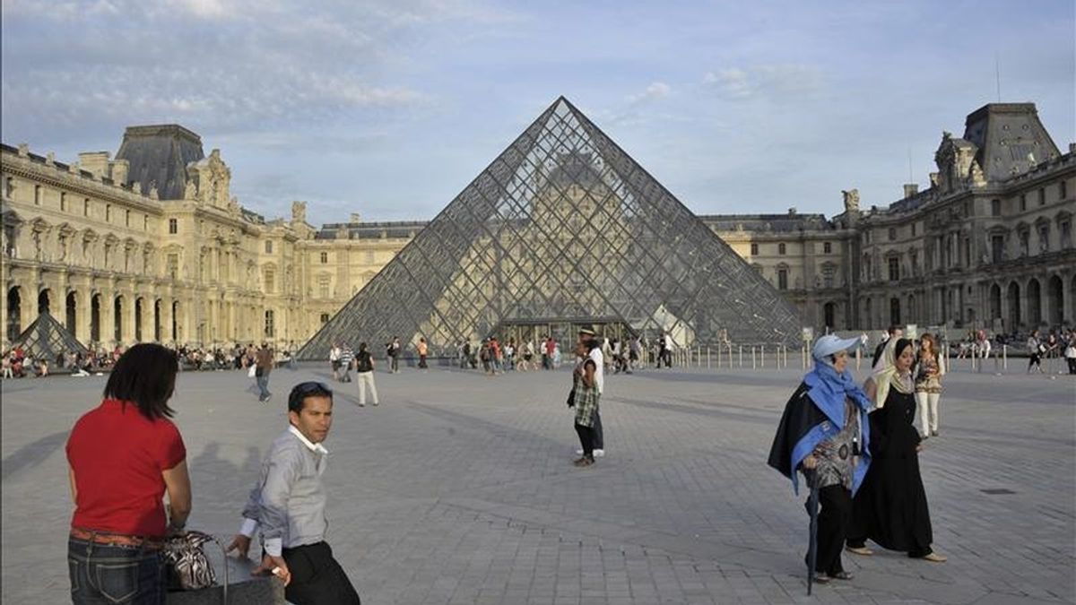 Paseantes caminan frente a la pirámide del Museo de Louvre. EFE/Archivo