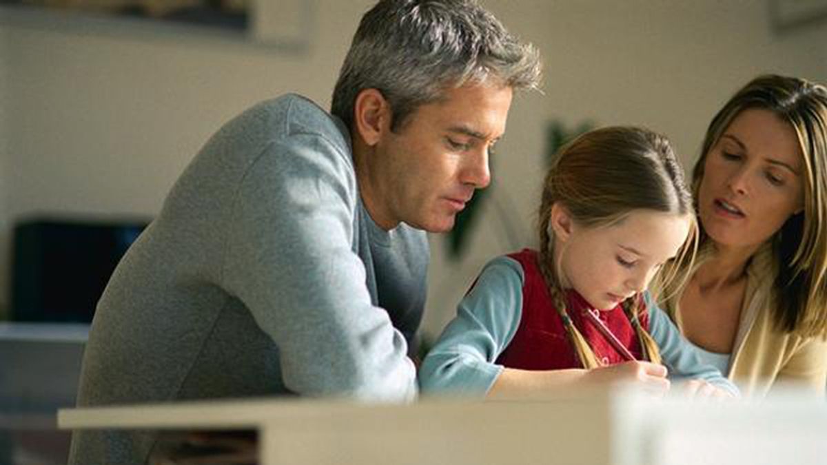 Unos padres ayudan a su hija a realizar sus deberes