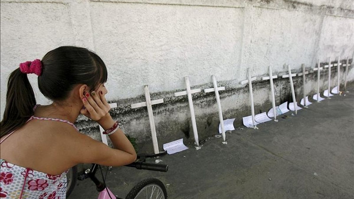 Una niña observa 12 cruces representando las víctimas de la masacre en la escuela Tasso da Silveira en Río de Janeiro (Brasil). La tragedia irrumpió en esa escuela este jueves cuando un exalumno mató a por lo menos doce niños e hirió a otros doce, antes de suicidarse. EFE