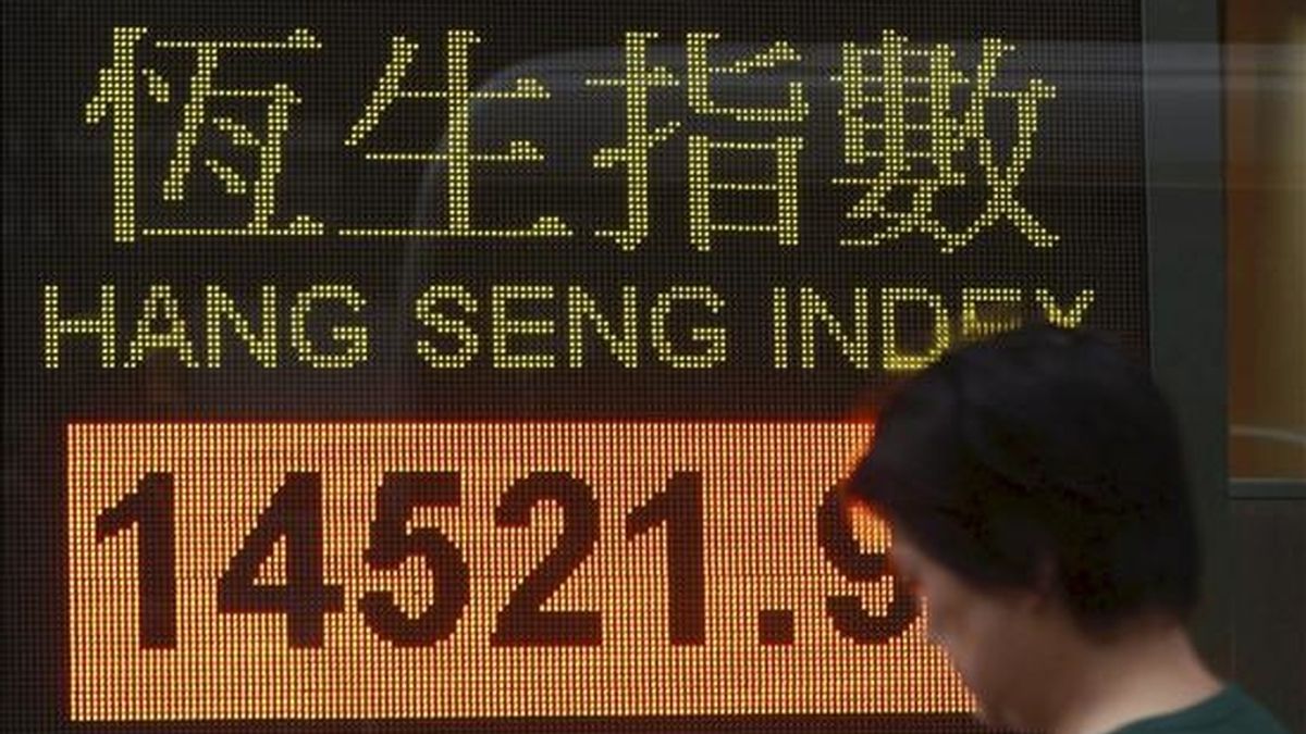 Una mujer camina cerca de un panel electrónico de un banco que muestra el índice de la bolsa de Hang Seng en la ciudad de Hong Kong. EFE/Archivo