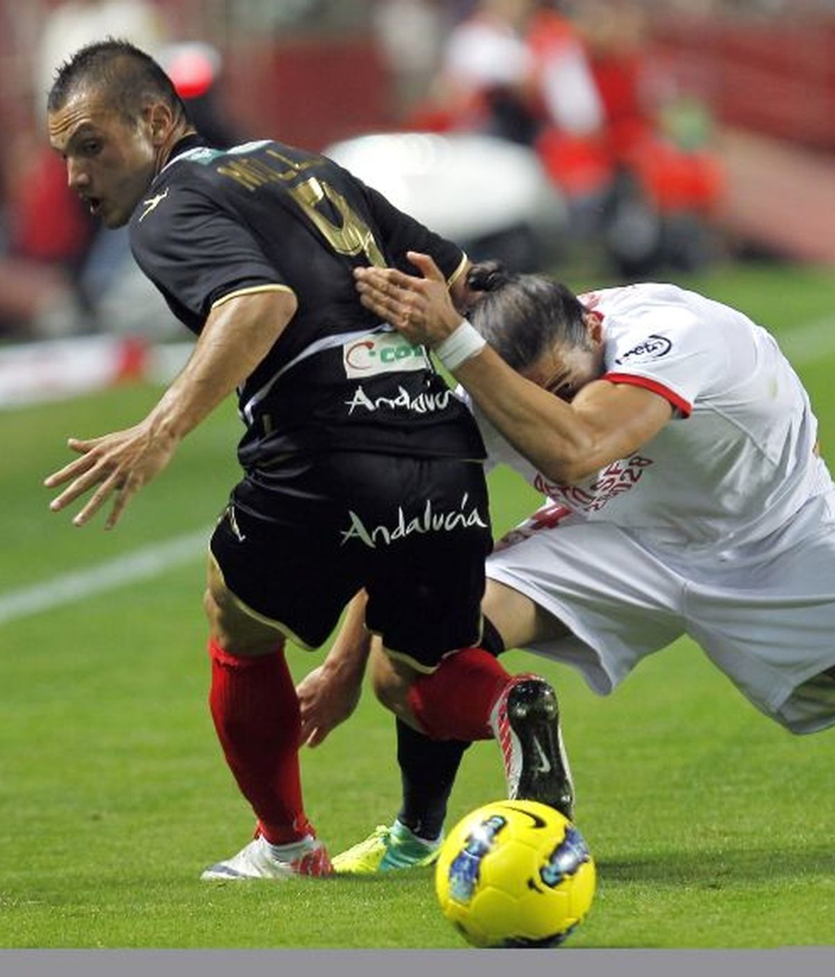 Martín Cáceres (d), del Sevilla, y Mollo, del Granada, en una jugada del partido de Liga que estos dos equipos juegan esta noche en el estadio Sánchez Pizjuán de Sevilla. Foto: EFE.