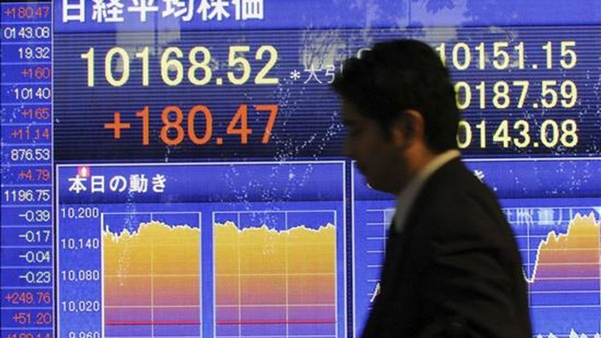 Un hombre pasa por delante de una pantalla que refleja EL índice Nikkei de la Bolsa de Valores de Tokio. EFE/Archivo