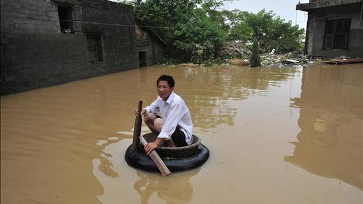 Un hombre rema en un improvisado bote inflable por una calle inundada de la ciudad de Fuzhou (China). EFE/Archivo