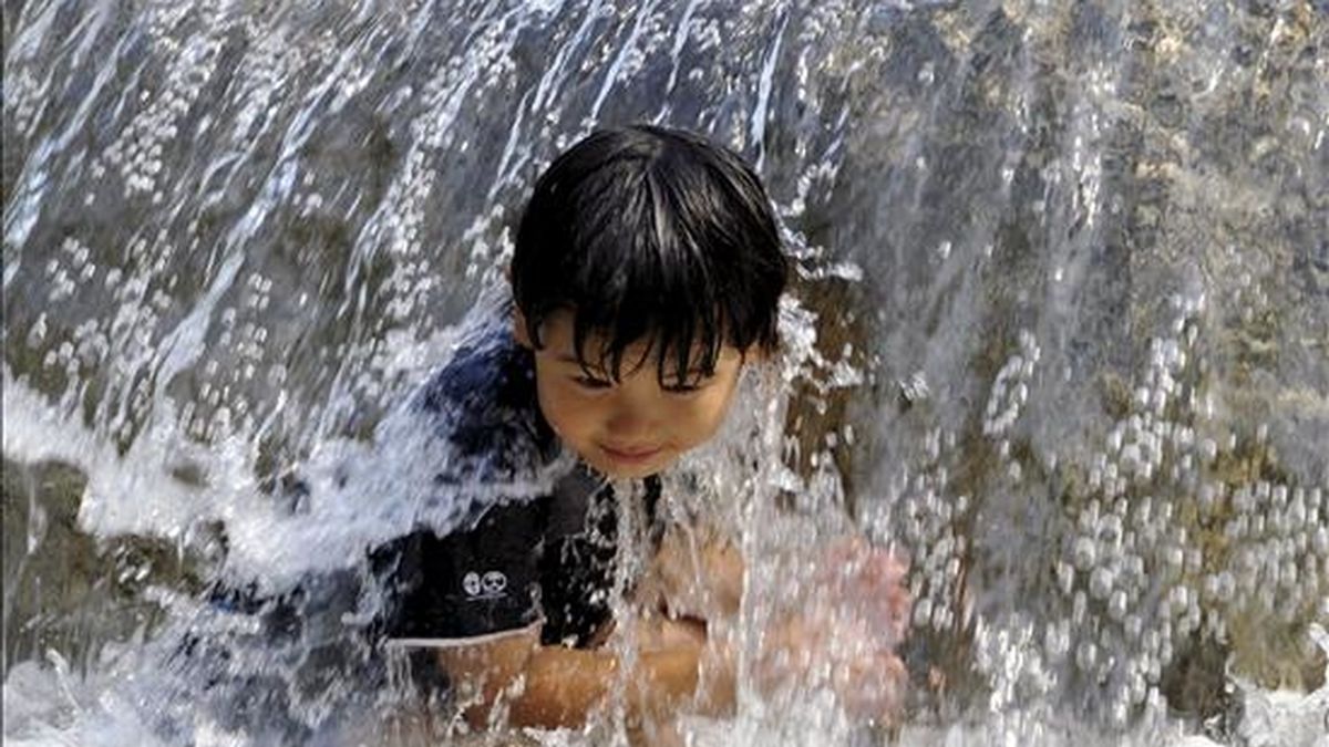 Un niño juega con el agua en una fuente. EFE/Archivo