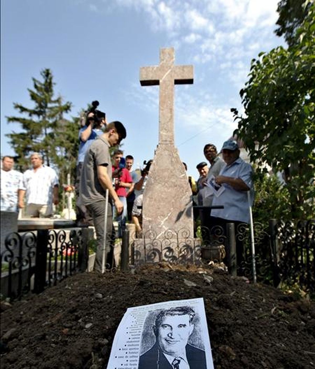 Periodistas y seguidores de Nicolae Ceausescu congregados delante de la tumba del que fue dictador comunista rumano, tras su exhumación en el cementerio de Ghencea, en Bucarest, este miércoles. EFE