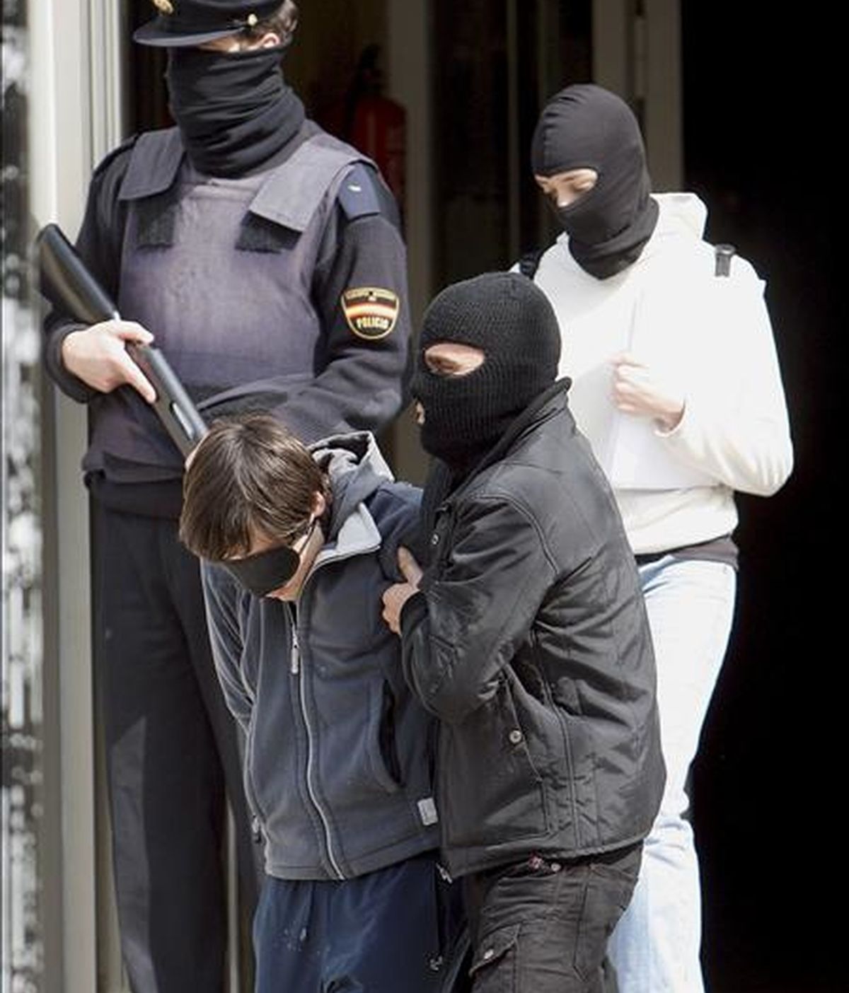 Agentes de la Policía Nacional trasladan desde la Subdelegación del Gobierno en San Sebastián a uno de las ocho personas (i) que han sido detenidas durante la madrugada en Hernani. EFE