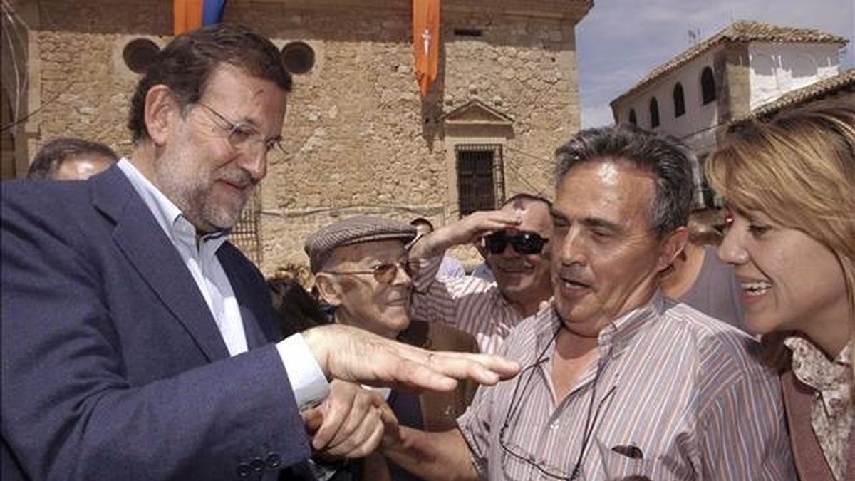El presidente del Partido Popular, Mariano Rajoy (i), junto a la presidenta del PP de Castilla-La Mancha y secretaria general nacional, María Dolores Cospedal (d), saluda a un grupo de vecinos a su llegada a la localidad toledana de El Toboso. EFE