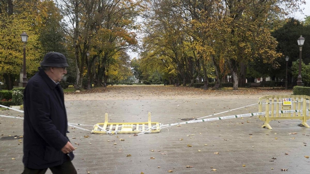 Un hombre camina por el exterior del Parque Rosalía de Castro, en Lugo, que se ha mantenido cerrado a causa de las fuertes rachas de viento previstas
