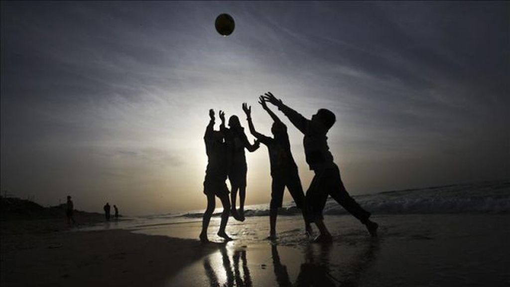 Niños jugando al fútbol en la playa