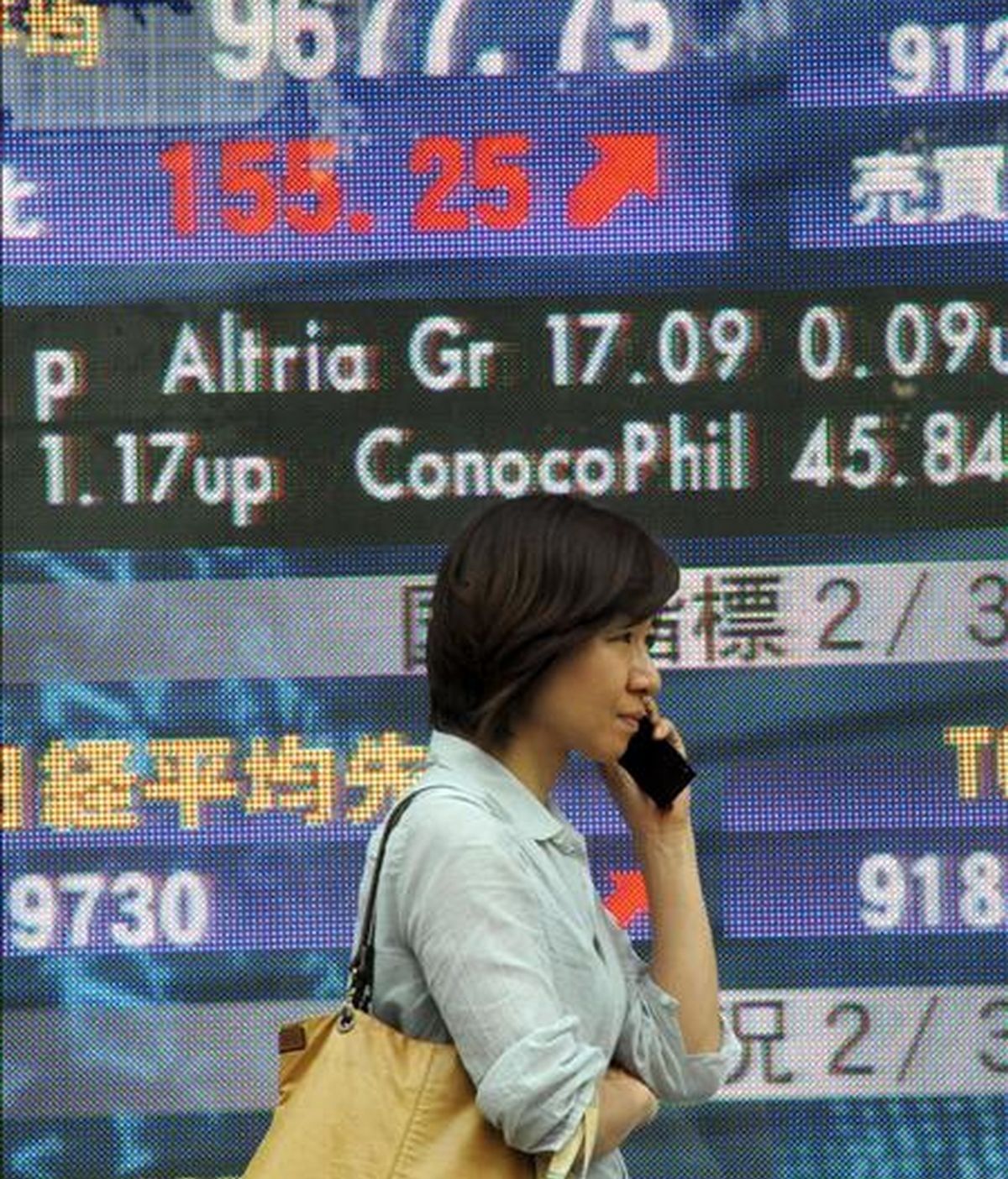 Un peatón pasa por delante de una pantalla electrónico con el valor del índice Nikkei, en el centro de Tokio, Japón. EFE