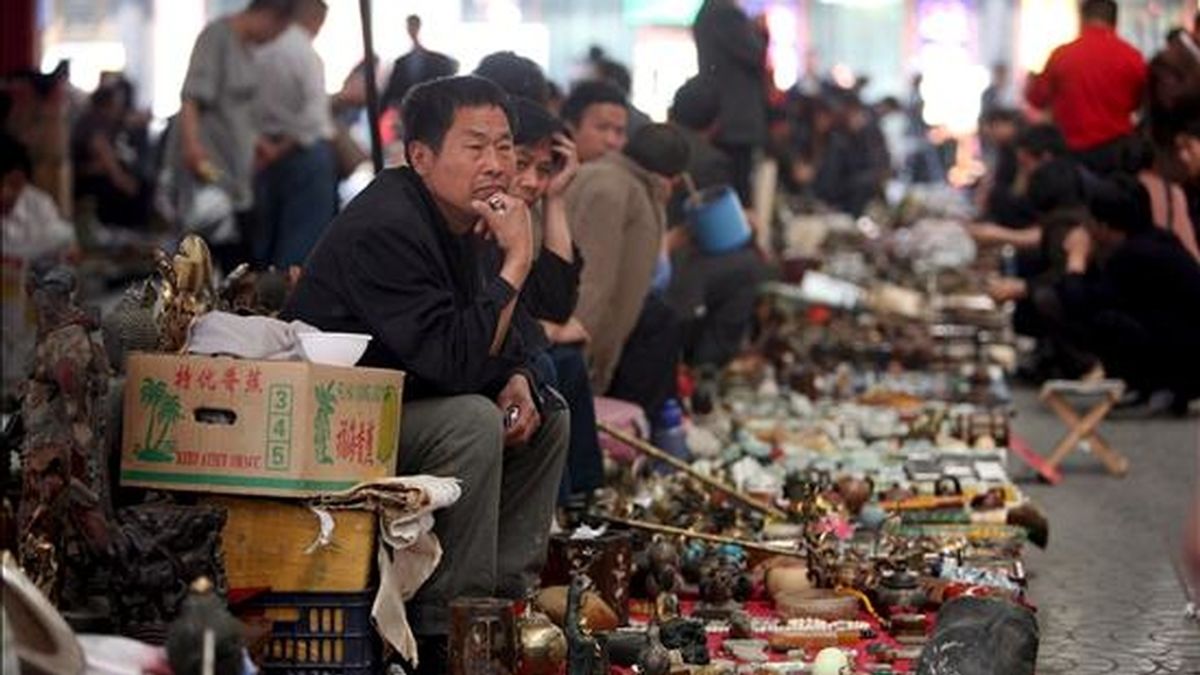 En la imagen, los vendedores de un mercado de Pekín, esperan la llegada de clientes hoy. EFE
