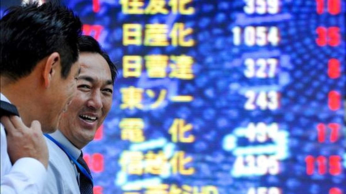 Dos ejecutivos japoneses caminan frente a un tablero electrónico con los índices de la Bolsa de Tokio, Japón. EFE/Archivo