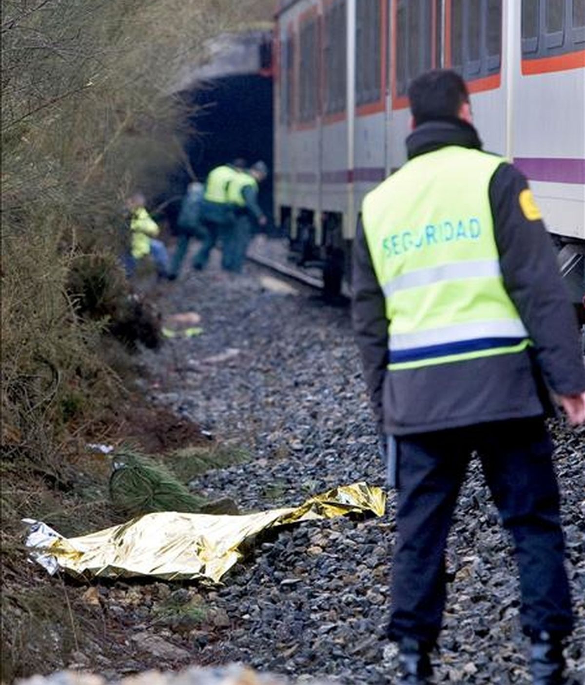 Un guardia jurado observa el cuerpo sin vida de una persona que ha muerto esta mañana al ser arrollada por un tren en la vía férrea que discurre entre A Coruña y Vigo, a su paso por la localidad coruñesa de Cerceda. EFE
