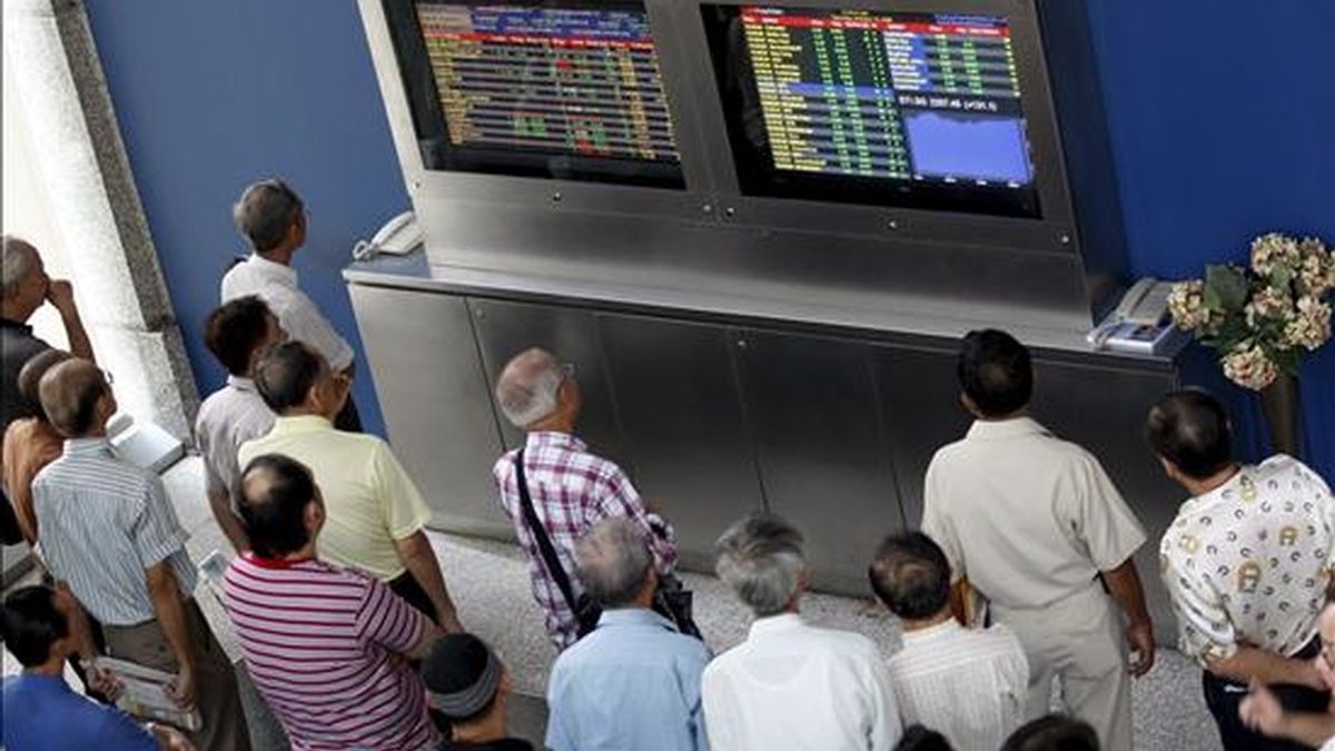 Un grupo de inversores observa unos monitores en los que se muestran los valores de la Bolsa de Singapur. EFE/Archivo