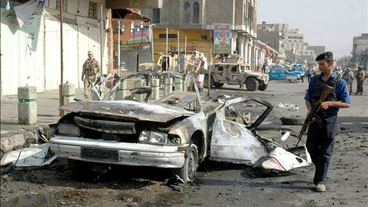 Policías iraquíes inspeccionan los restos de un vehículo utilizado hoy en un atentado con coche bomba en Bagdad. EFE