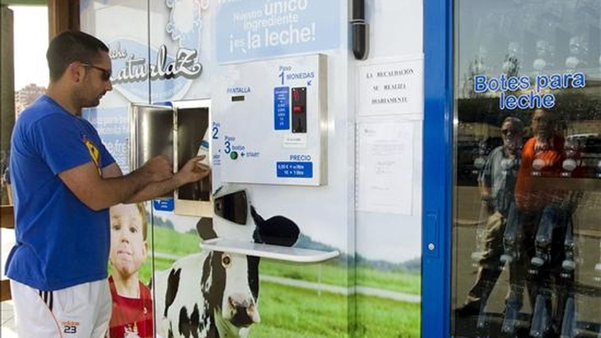 Un joven saca una botella de leche de la máquina expendedora instalada en un centro comercial de Zamora. EFE