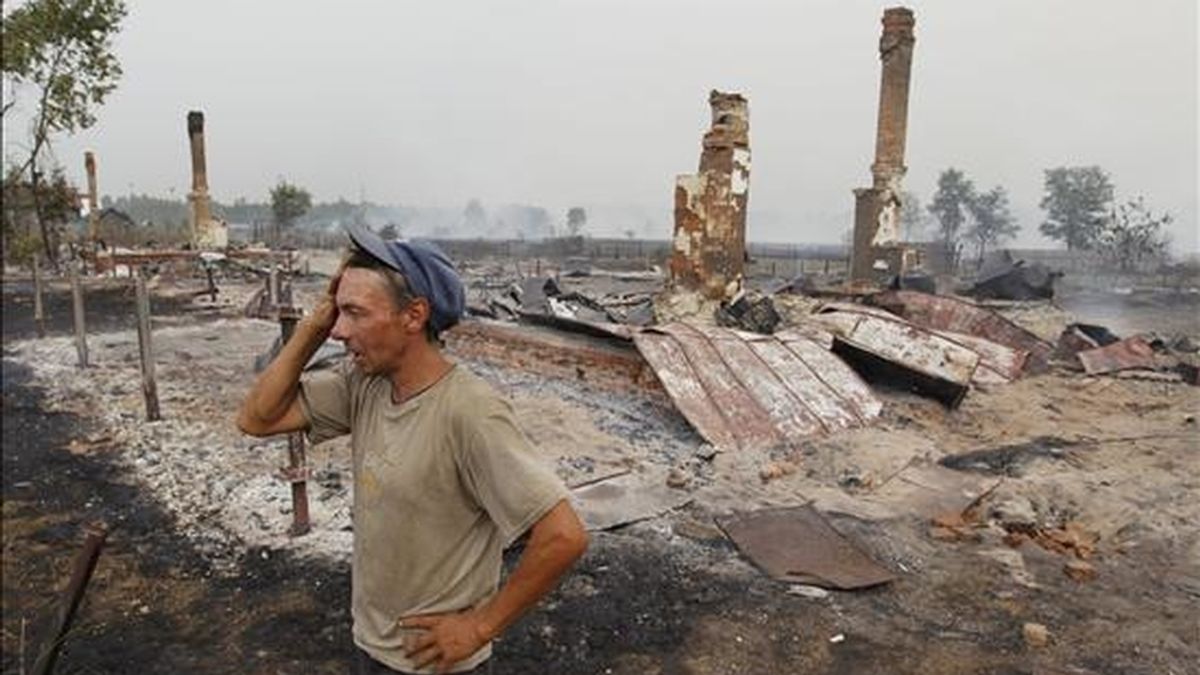 Un hombre junto a su casa quemada por el fuego en la localidad rusa de Mokhovoye, a unos 170 kilómetros de Moscú, este viernes. EFE