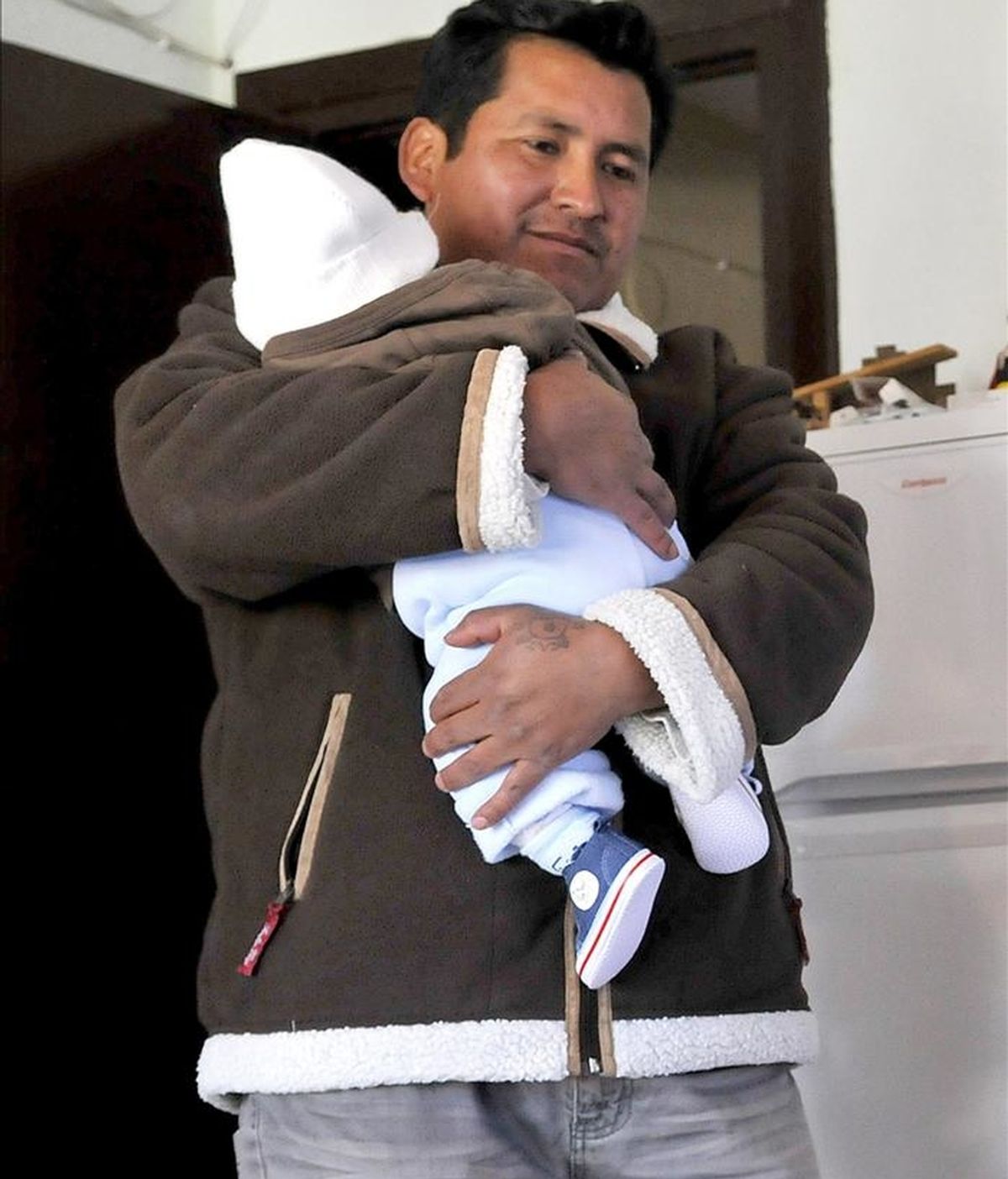 Wilson Godoy, padre del bebé secuestrado el pasado lunes en Granada por una mujer de nacionalidad boliviana de 30 años, con su hijo Alexander en su casa después de que la Policía Nacional lo recuperase tras 24 horas de la desaparición. EFE