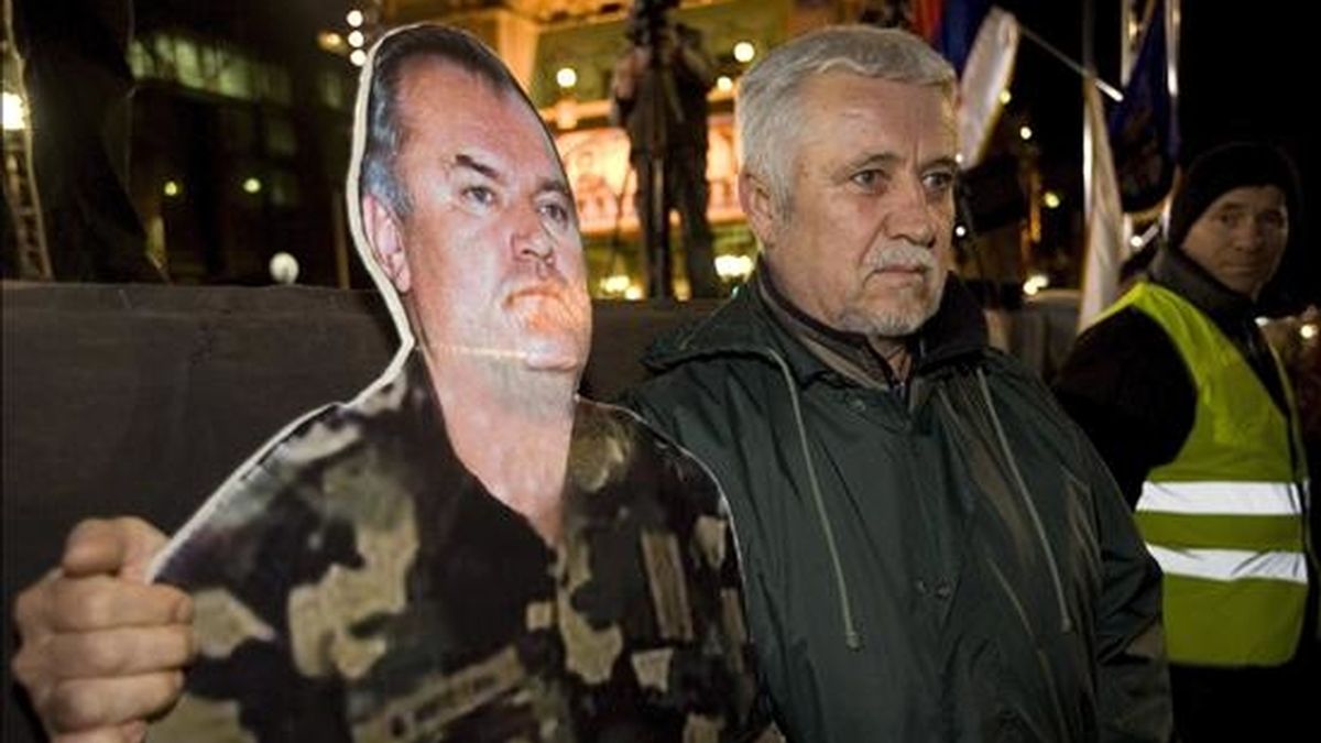 Un manifestante permanece junto a una fotografía del general serbo-bosnio Ratko Mladic , durante una protesta que se celebró el 24 de marzo en Belgrado (Serbia), con motivo de la celebración del décimo aniversario de los bombardeos de la OTAN. EFE