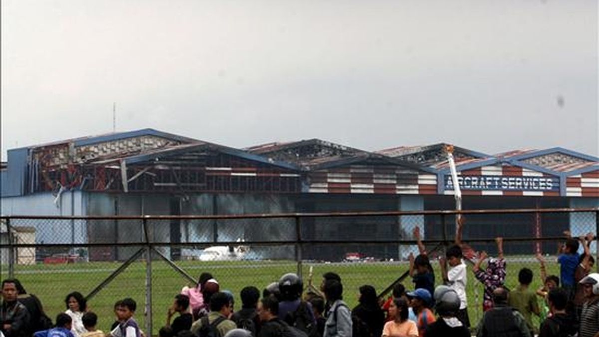 Decenas de personas observan el hangar del aeropuerto Hussein Sastranegara, de Badung, Java (Indonesia), dañado en un accidente aéreo, el 6 de abril de 2009. Al menos 25 personas murieron hoy tras estrellarse un avión militar contra un hangar en una base aérea en el oeste de la isla indonesia de Java, informó el portavoz de la Fuerza Aérea, Bambang Sulistyo. EFE