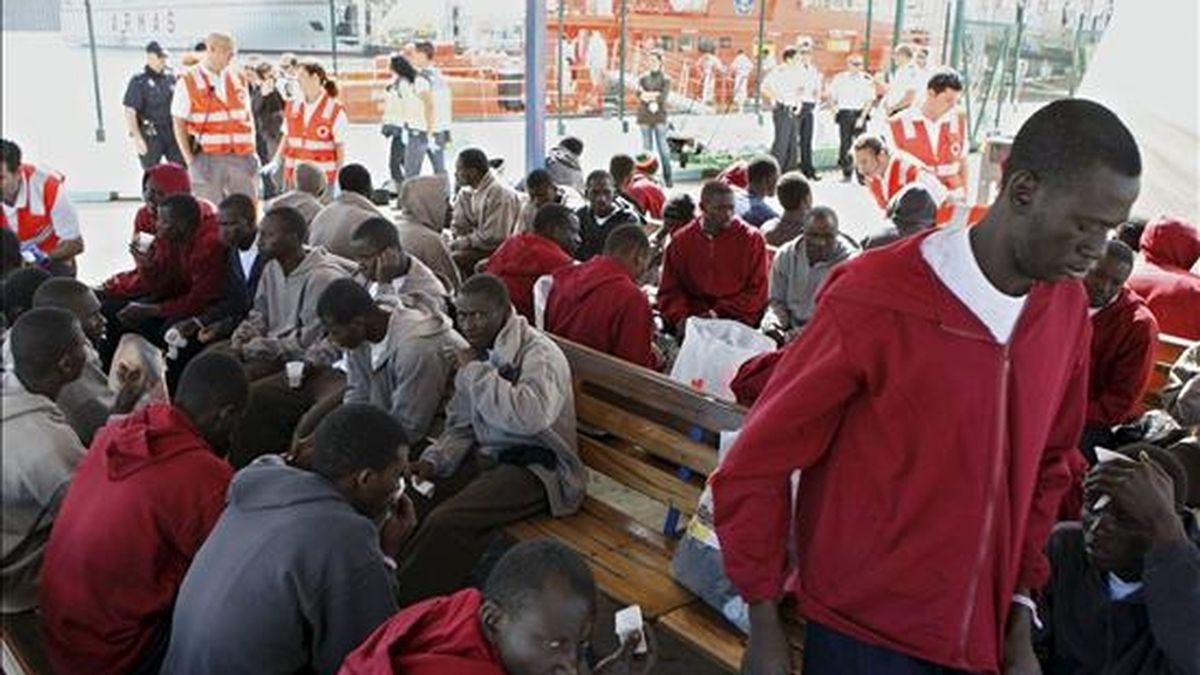 Los 67 inmigrantes que han sido rescatados de un cayuco cerca de la costa del sur de Tenerife, y entre los que se encontraban cinco posibles menores de edad, esperan para ser trasladados tras recibir asistencia a su llegada al puerto de Los Cristianos. EFE