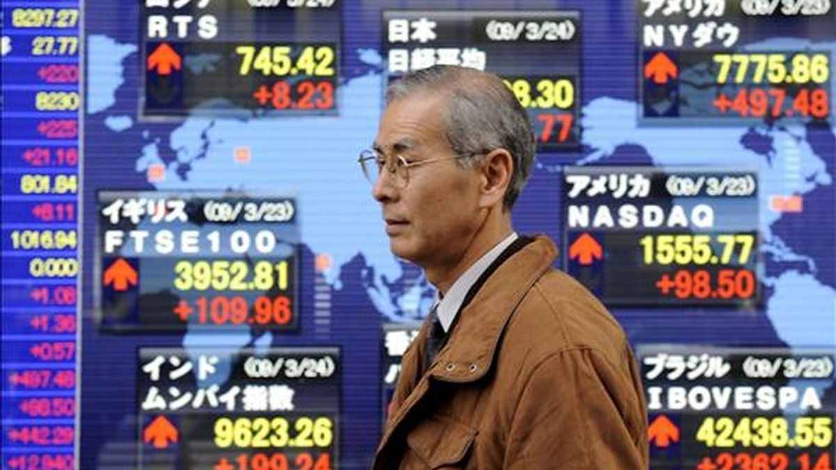 Un hombre pasa por delante de un panel electrónico en el que se muestran los valores de la Bolsa, en Tokio. EFE/Archivo