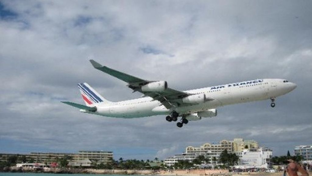 Maho Beach (St. Maarten, Caribe). Desde la orilla los bañistan ven a los aviones aterrizar y despegar