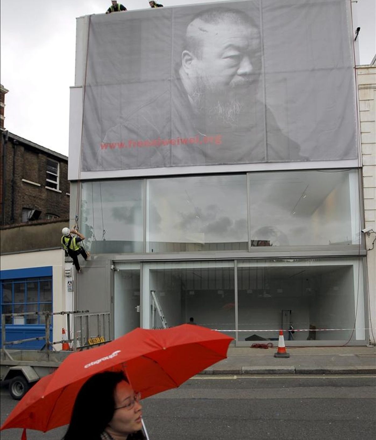 Unos trabajadores despliegan un gran cartel con un retrato en blanco y negro del artista chino Ai Weiwei antes de la inauguración de una exposición retrospectiva sobre los últimos seis años de su obra en la galería Lisson en Londres, Reino Unido. EFE
