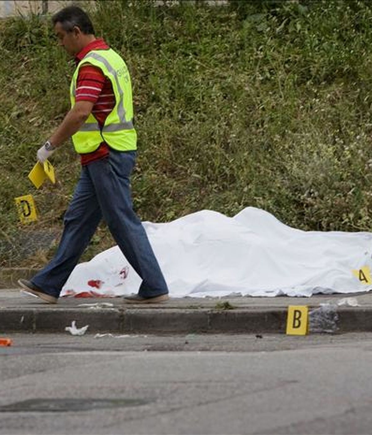 Un agente de la Guardia Civil junto al cuerpo de uno de los dos fallecidos en un tiroteo en las proximidades del polideportivo de Ujo, un pueblo del municipio asturiano de Mieres. EFE