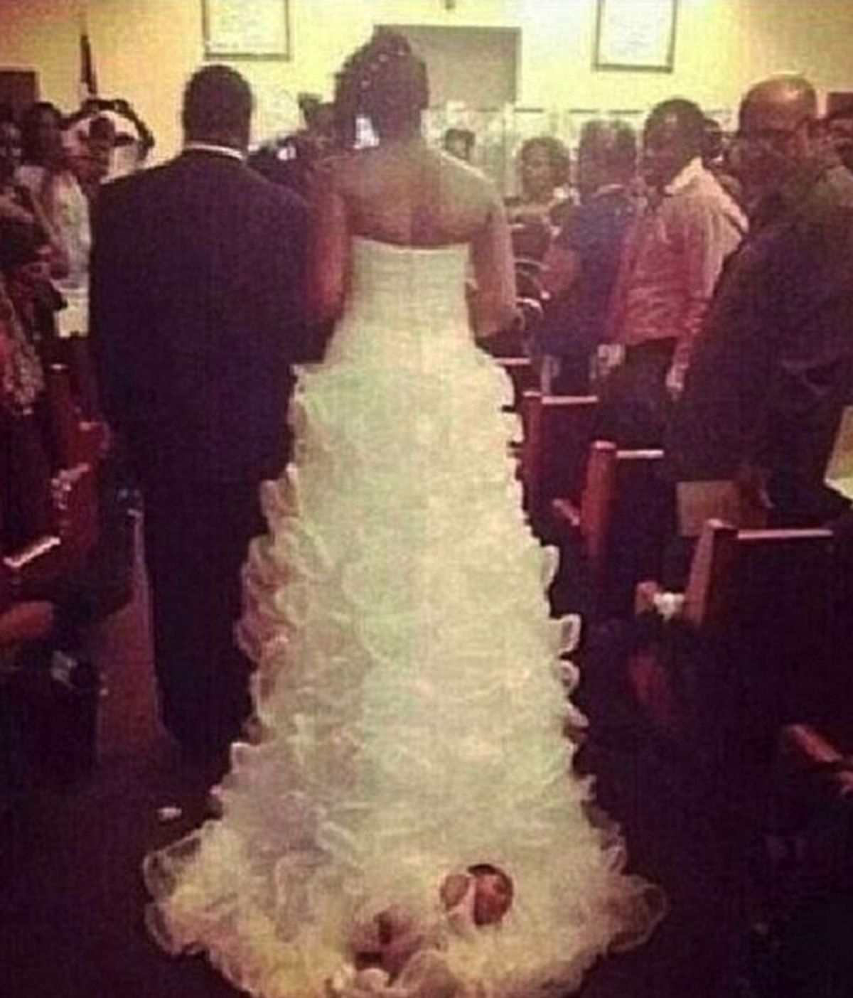 Una mujer en su boda ata en el vestido a su hijo
