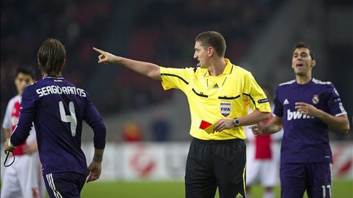 El árbitro Craig Thomson (c) saca la tarjeta roja al jugador del Real Madrid Sergio Ramos, durante el partido de Liga de Campeones que su equipo disputó ante el Ajax de Amsterdam el pasado 23 de noviembre. EFE/Archivo