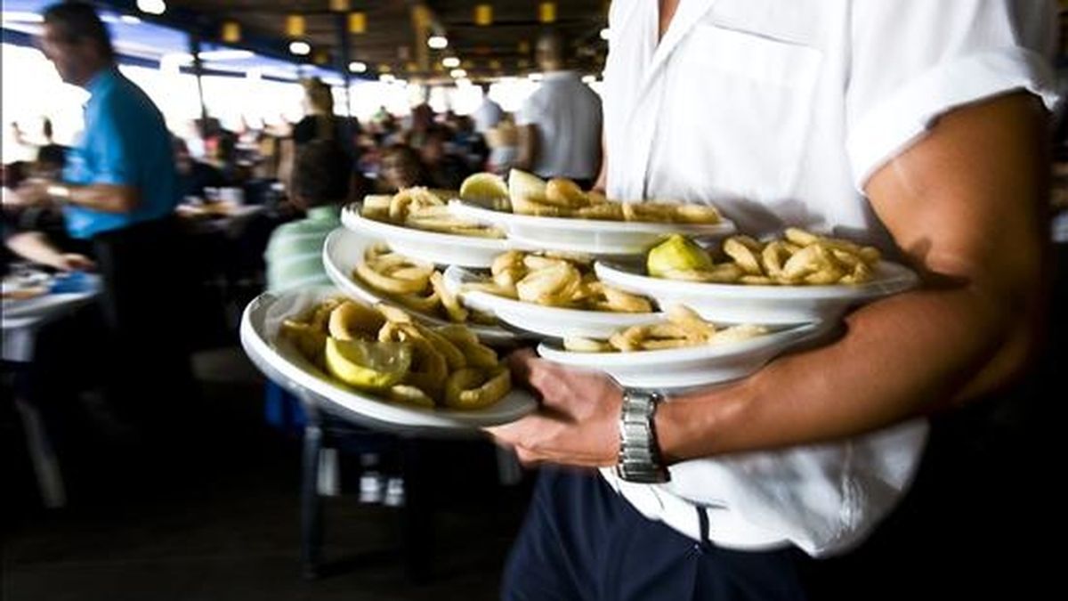 Un camarero porta varios platos en un chiringuito de Málaga. EFE/Archivo