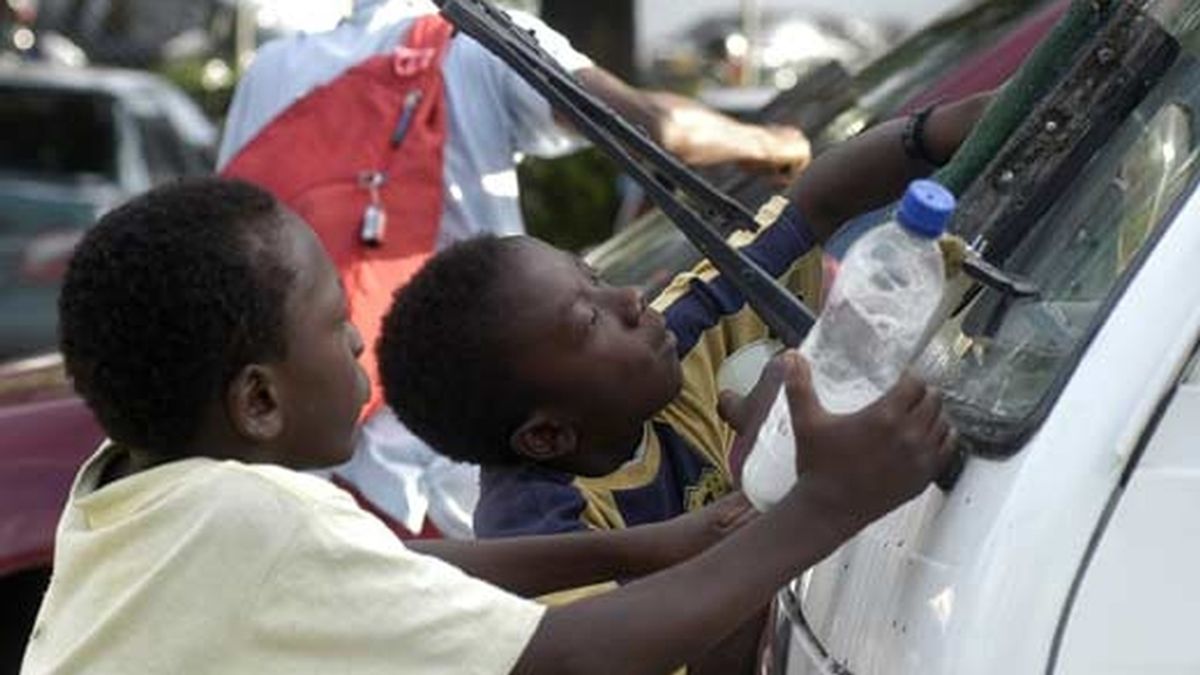 Dos niños colombianos trabajan limpiando los parabrisas de algunos vehículos que se detienen en los semáforos. Foto: EFE