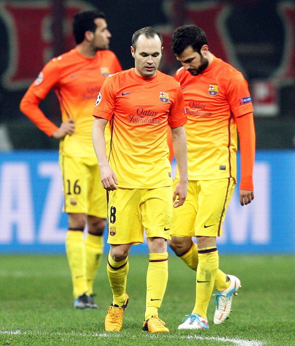 Los centrocampistas del FC Barcelona, Andres Iniesta y Cesc Fábregas (dcha), se lamentan tras recibir un gol del AC Milan, durante el partido de ida de los octavos de final de la Liga de Campeones disputado en el estadio Giuseppe Meazza de Milán