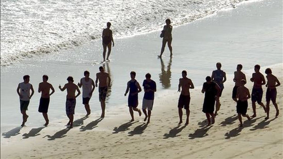 Un grupo de jóvenes corre por la playa de la Concha de la capital donostiarra, donde se esperan altas temperaturas que superen los 30 grados en las horas centrales del día. EFE