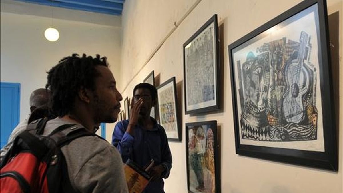 Jóvenes observan diferentes cuadros de las exposiciones "Farsa", del artista cubano Ignacio Fernández Mérida, y "El faro de la utopía", del español Juan Carlos Mestre, inauguradas ayer en La Habana (Cuba). EFE