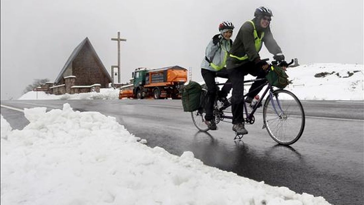 Dos ciclistas que realizan el Camino de Santiago en una bicicleta de tándem pasan por el alto de Ibañeta que permanece cubierto de nieve. EFE/Archivo