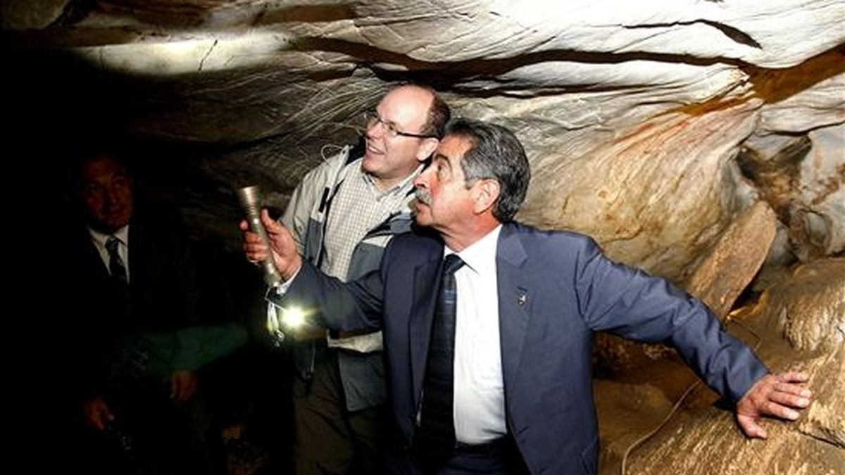 El presidente de Cantabria, Miguel Ángel Revilla (d), muestra al príncipe Alberto de Mónaco los grabados prehistóricos de uno de los techos de la cueva de El Castillo, en Puente Viesgo (Cantabria). EFE