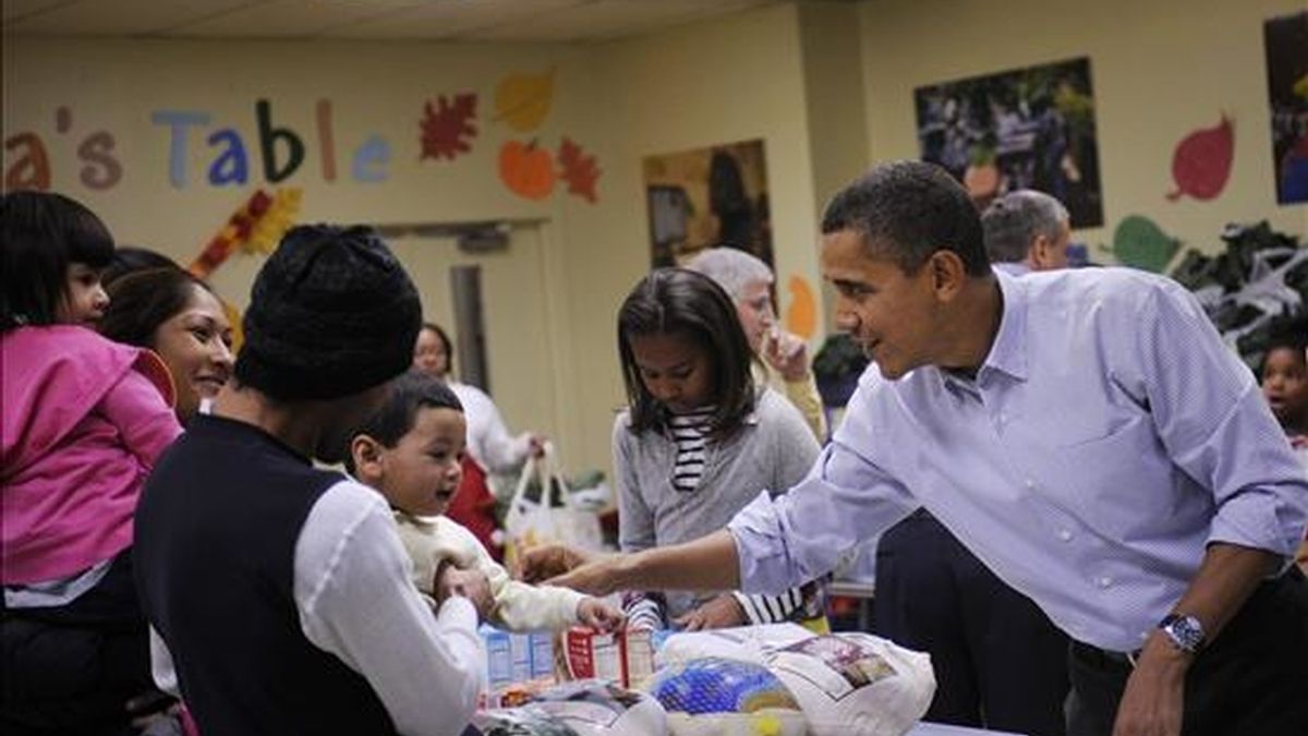 El presidente estadounidense Barack Obama (d) saluda a las personas beneficiadas en una jornada para repartir comida para la gente necesitada en Washington DC (EEUU), en la víspera de Acción de Gracias. EFE