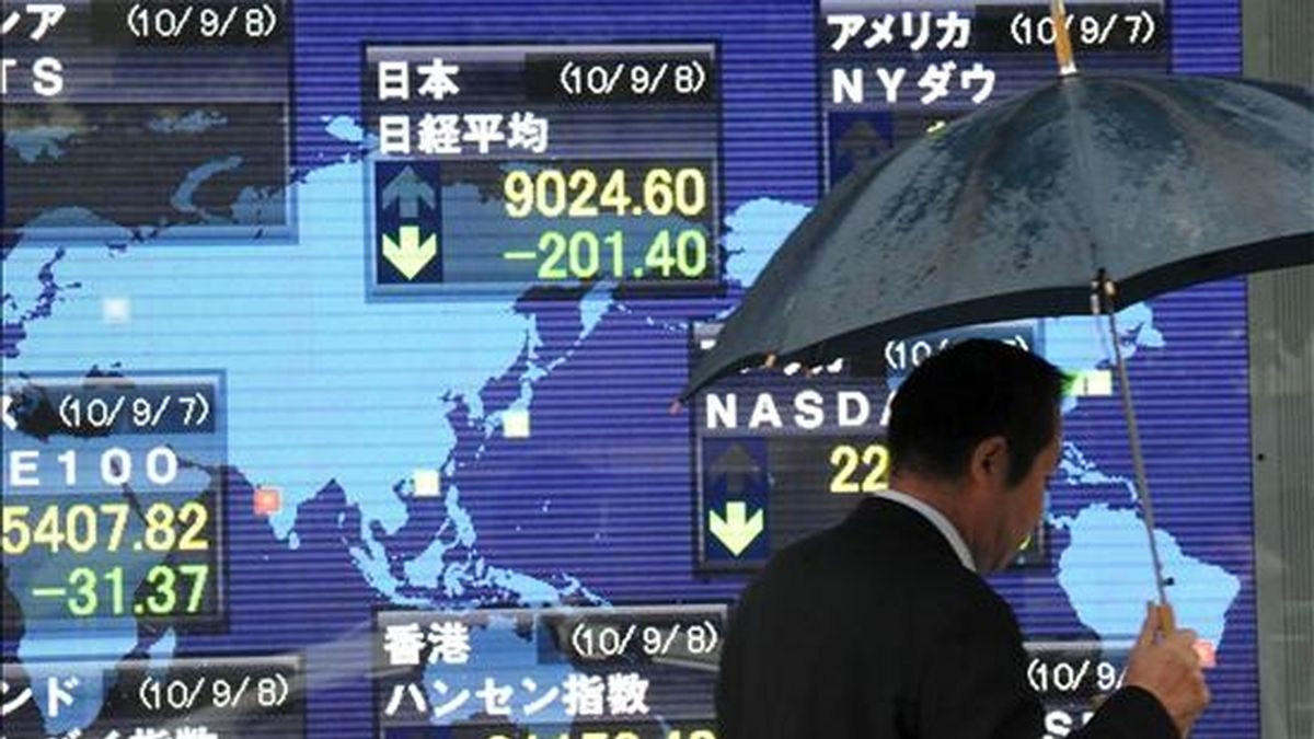 Un hombre pasa junto a una pantalla en la que se muestran los datos de los parqués internacionales, en Tokio (Japón). El índice Nikkei de la Bolsa de Valores de Tokio subió en su apertura un 0,67 por ciento. EFE