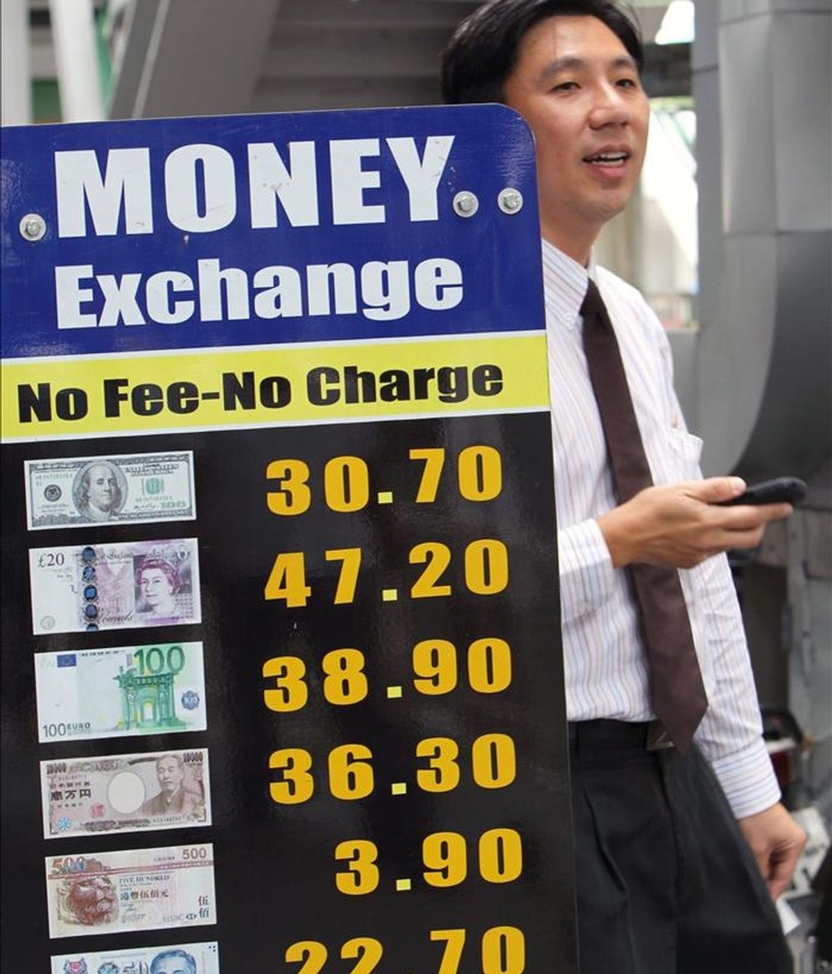 Un hombre camina junto a un tablero con los valores de distintas divisas en el distrito financiero de Bangkok, Tailandia. EFE/Archivo