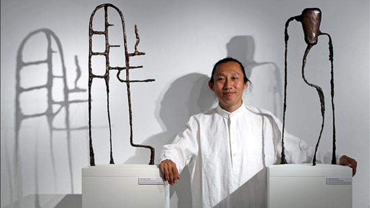 El artista chino Wang Xieda posa entre sus obras, Sages's Saying 013, y Sages's Saying 058. EFE